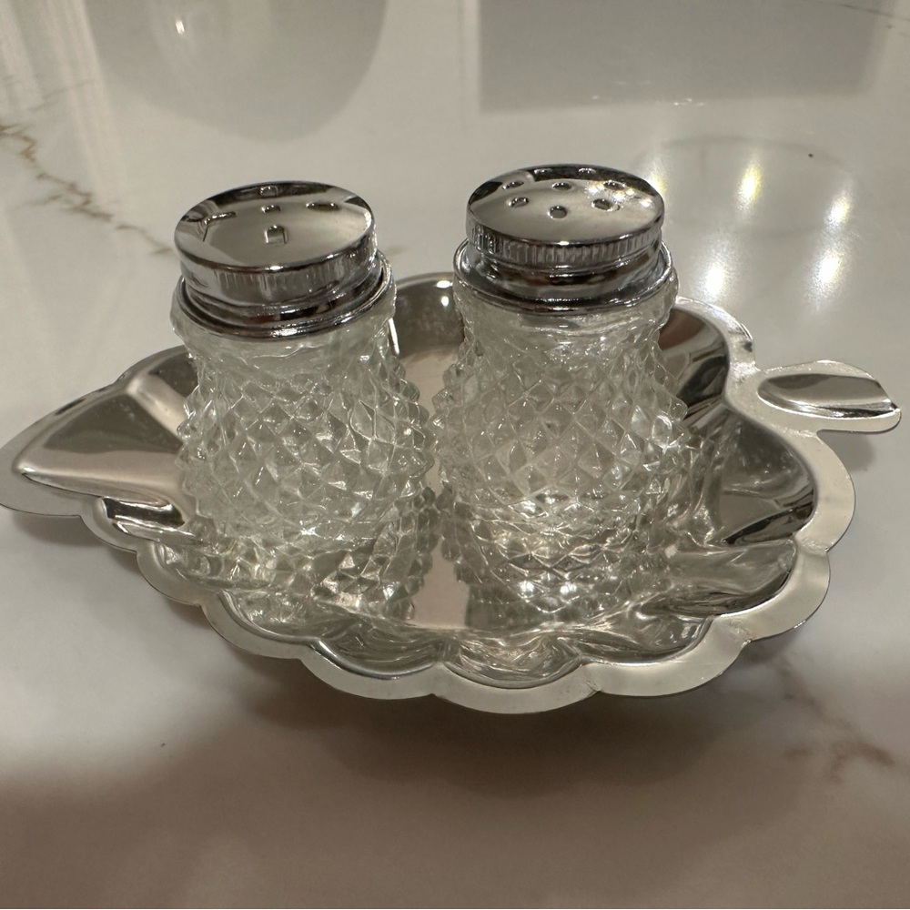Tiny crystal salt and pepper shakers on silver leaf tray